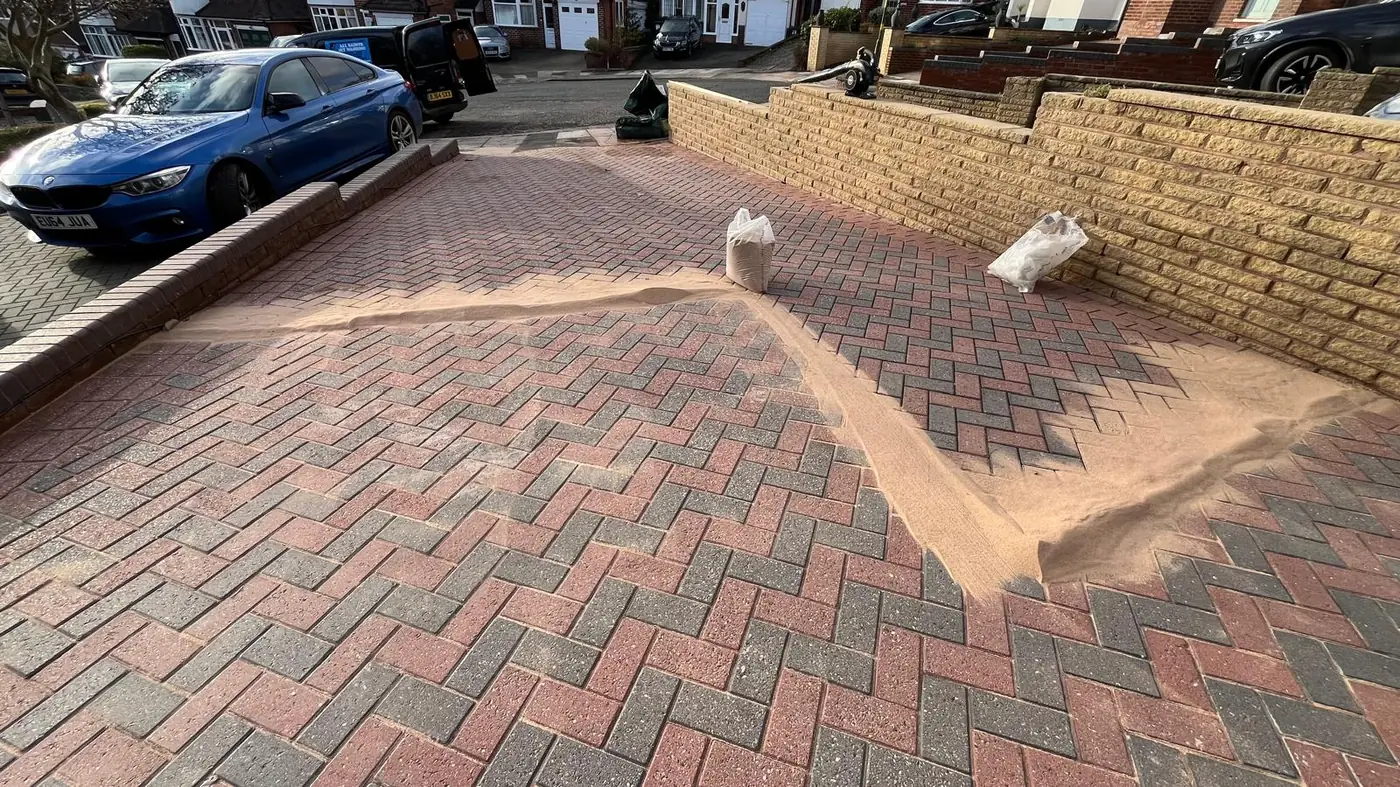Kiln-dried sand being brushed into block paving joints after jet washing in Bromsgrove